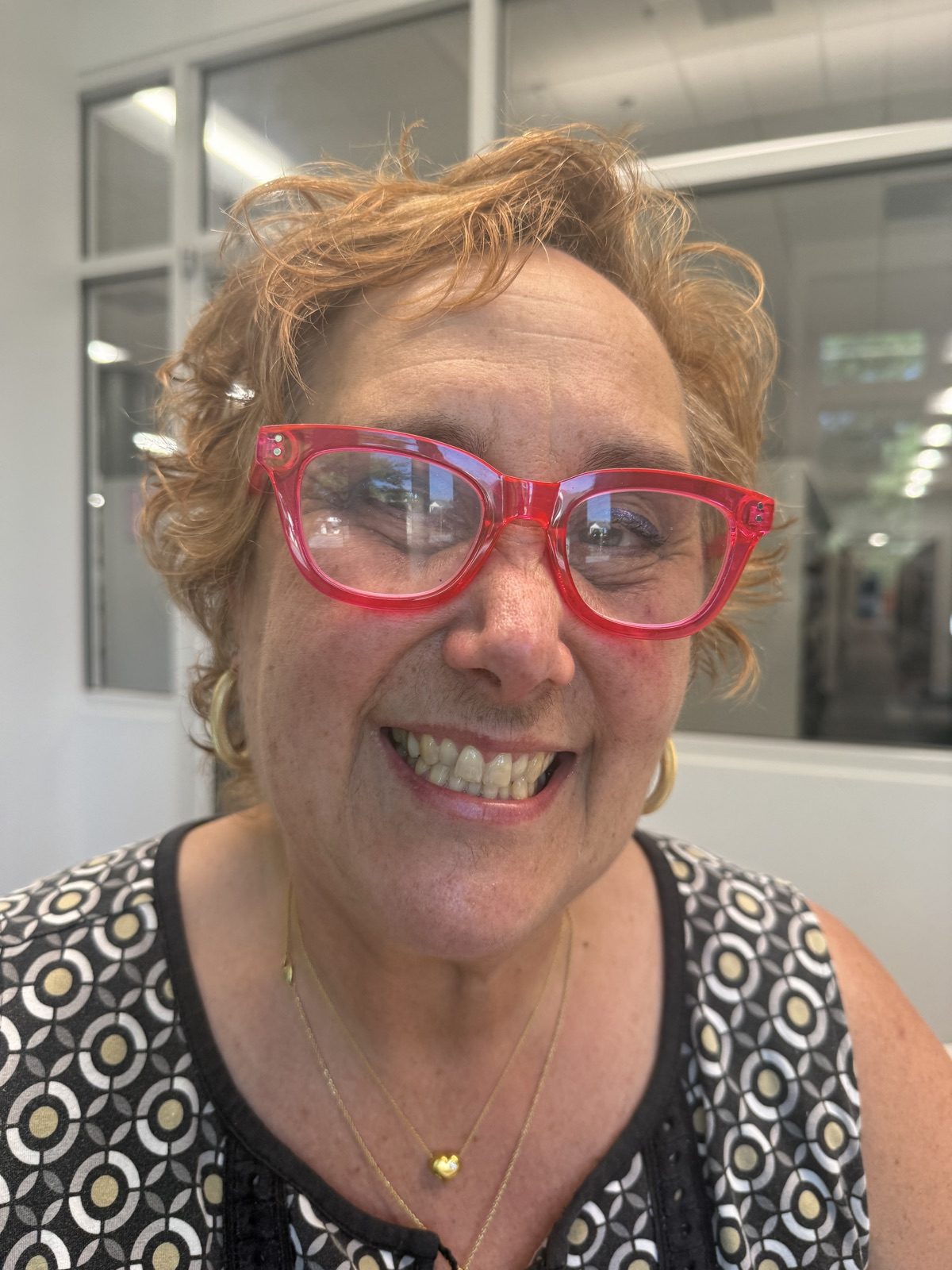 Terri Hitzig, smiling, in pink cat-eye glasses